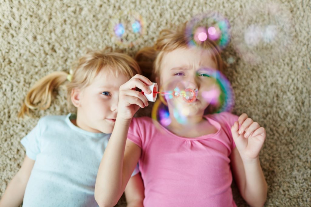 Young girls blowing bubbles at home