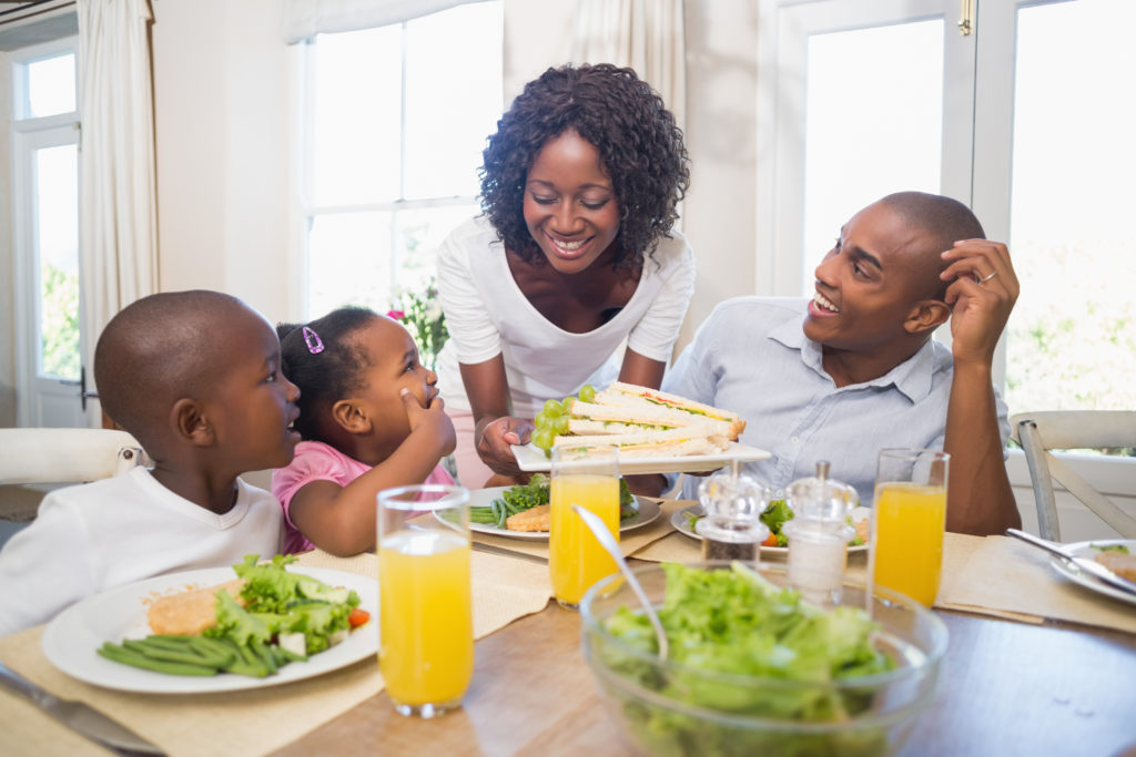 Family with young children at table enjoying meal together