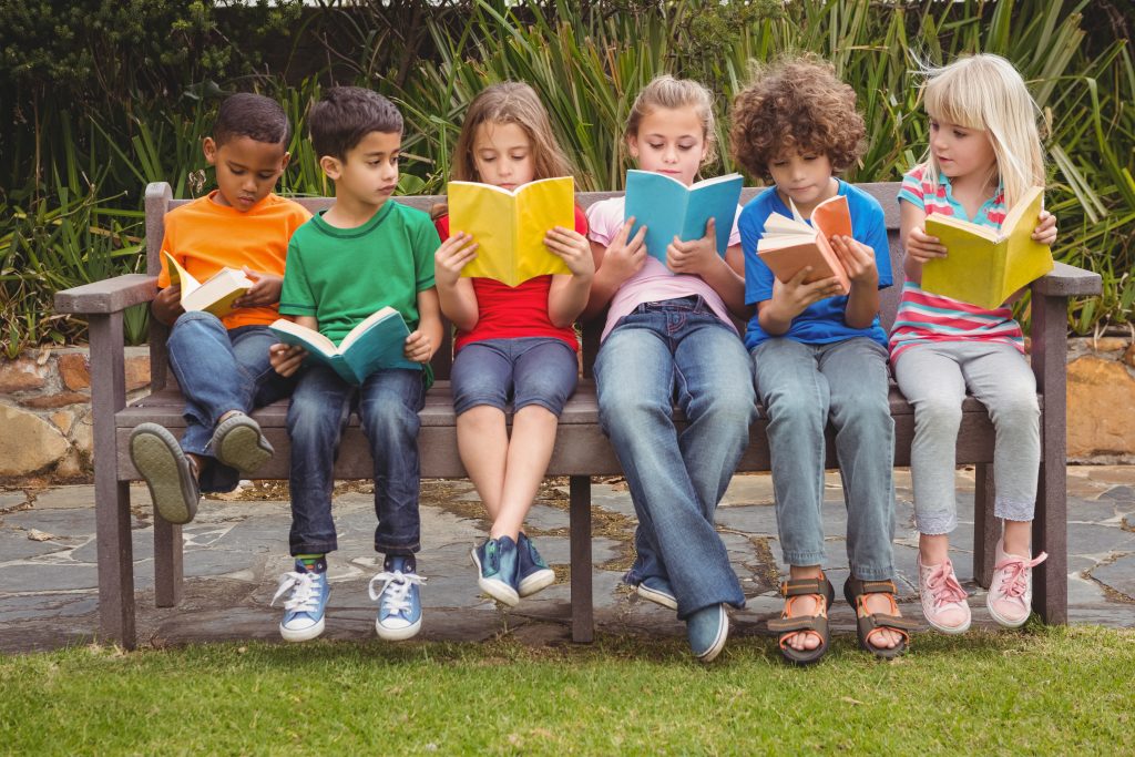 School-aged children reading on bench