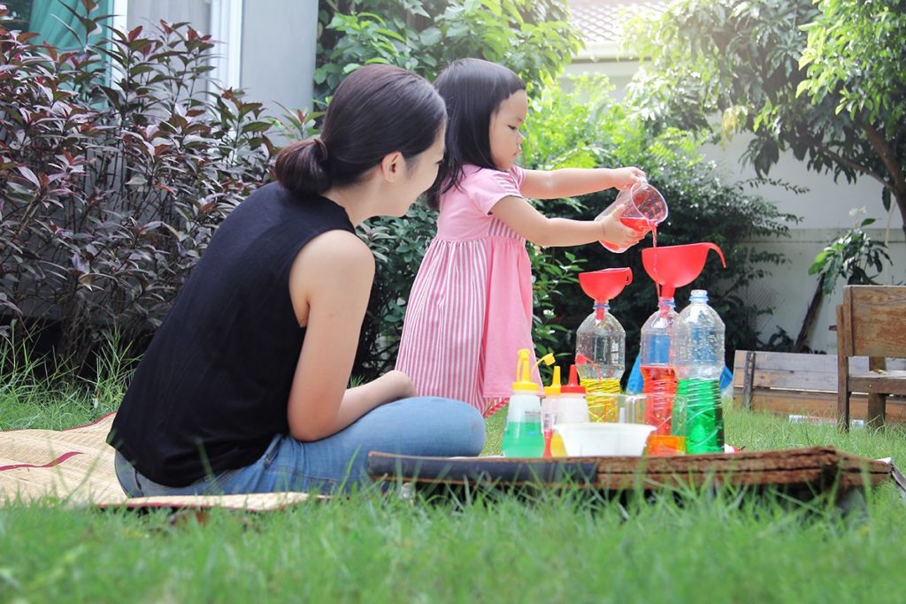Mom supervising child conduct science experiment that helps language development