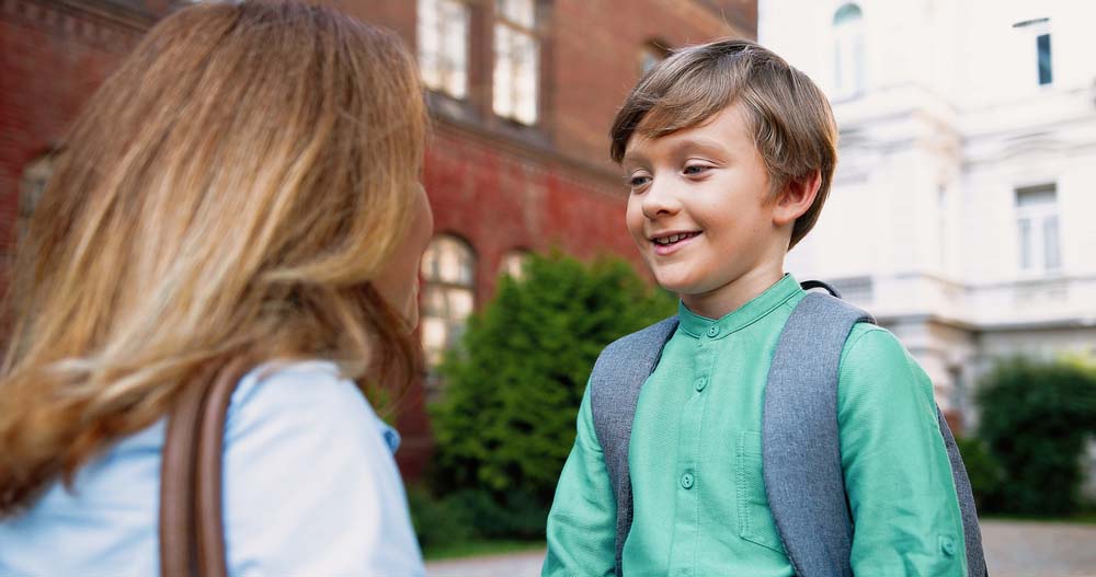 Mom talking with son at schoolyard outdoors