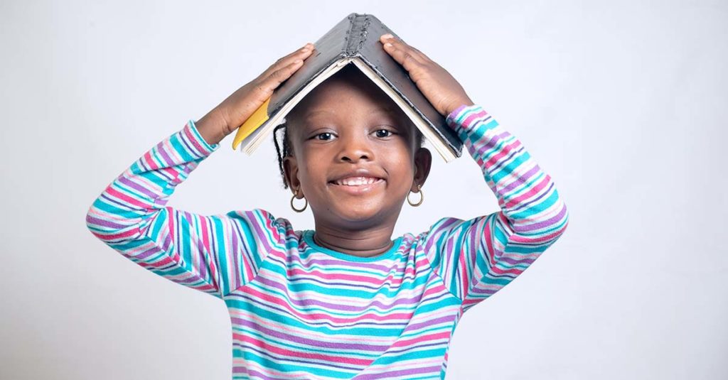Girl Smiling with Book on Her Head