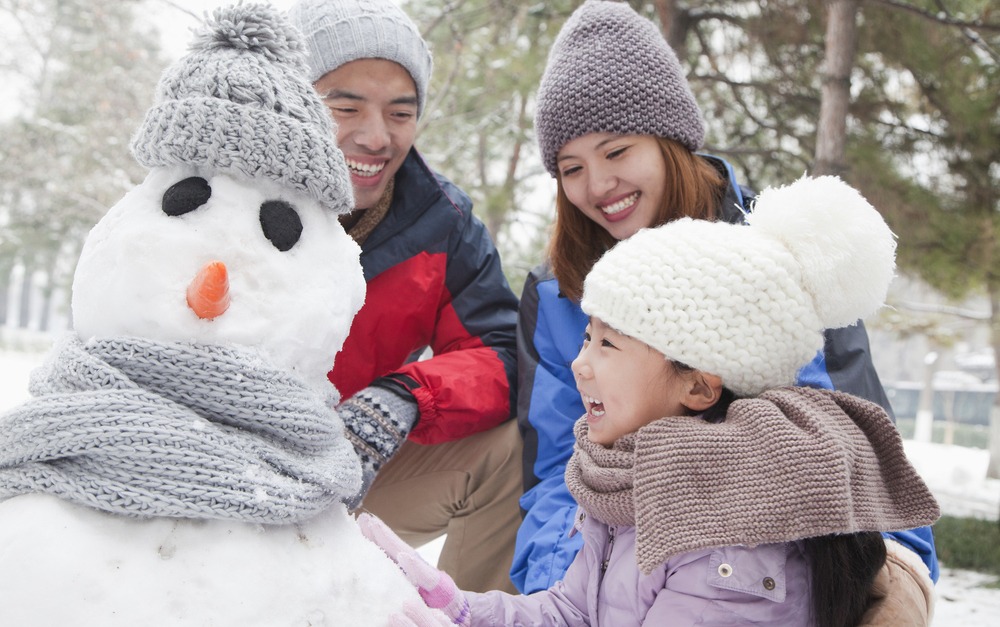 Girl Making Snowman With Parents Winter Activities