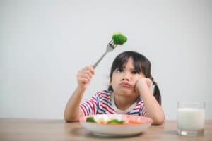 Child reluctantly eating vegetables