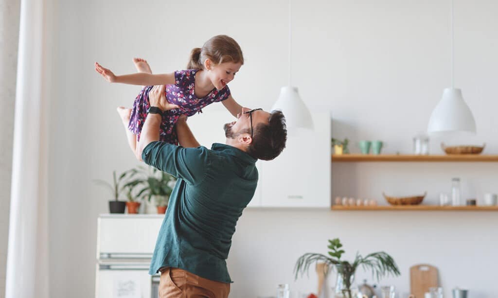 Father holding up smiling daughter