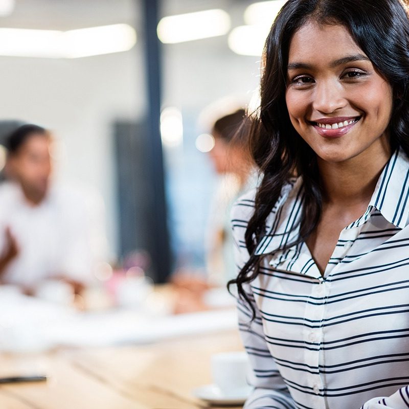 Woman smiling with others in the background during a meeting
