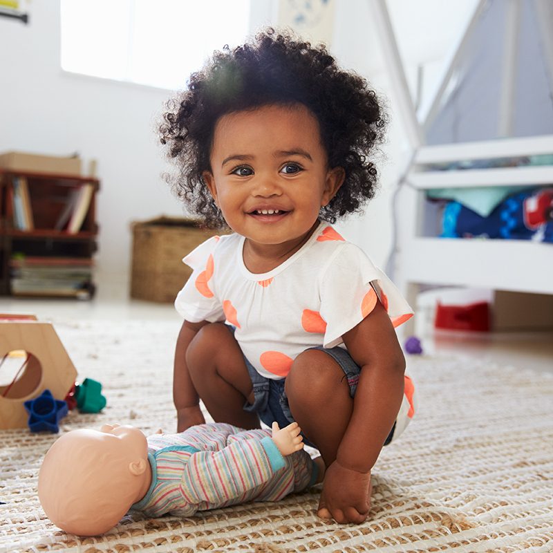 Smiling Toddler with Baby Doll