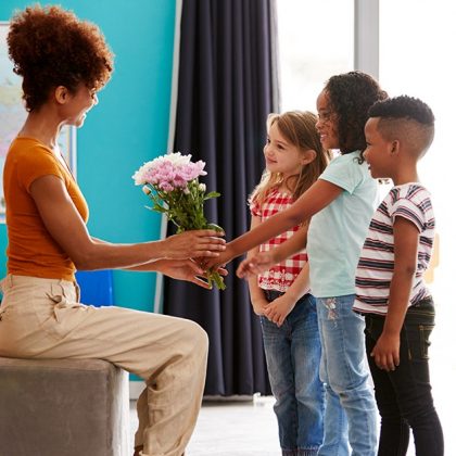 children handing teacher a bouquet of flowers