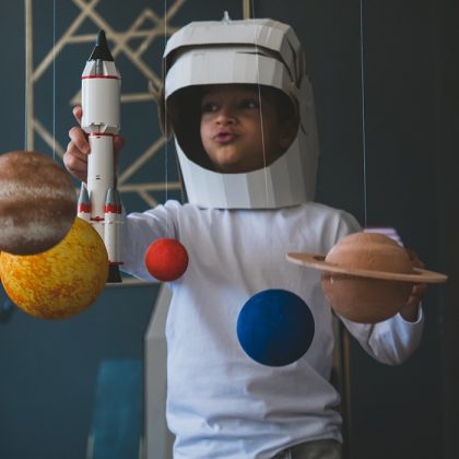Boy in an Astronaut Suit Surrounded by Planets