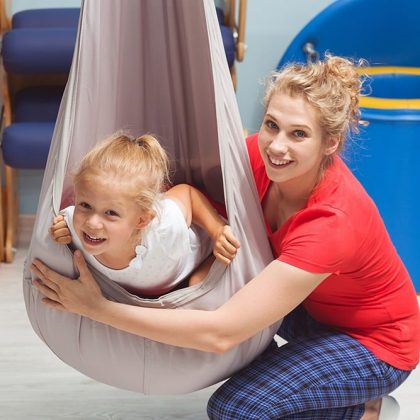 Therapist working with child hanging in a swinging pod